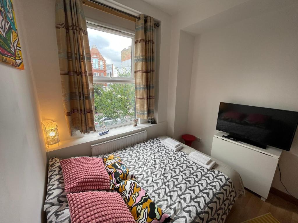 een kleine slaapkamer met een bed en een raam bij Spacious Family Flat in Londen