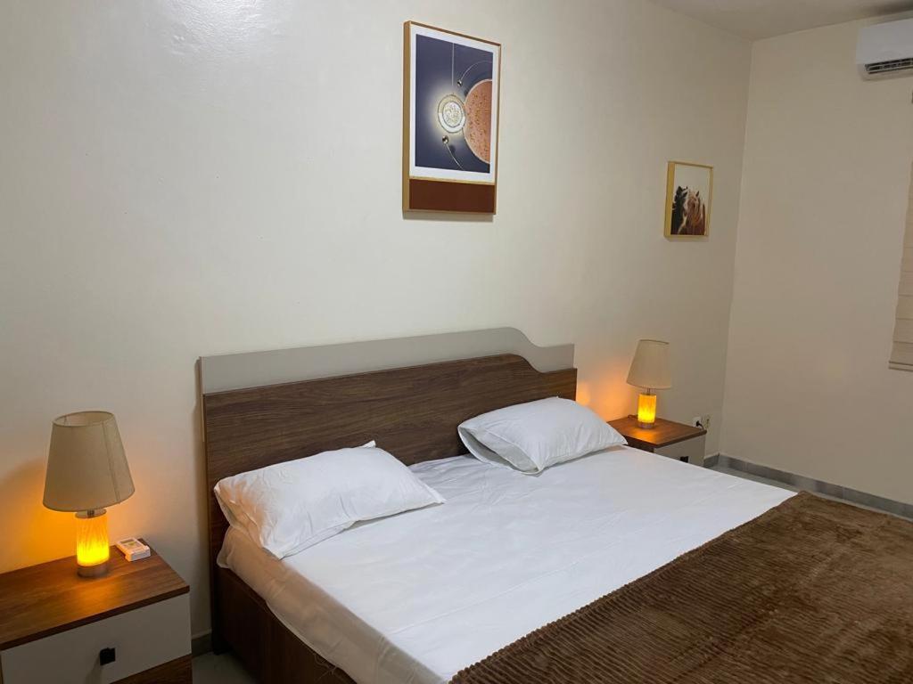 a bedroom with a large bed with two lamps at CHEZ CODOU FANN RESIDENCE in Dakar