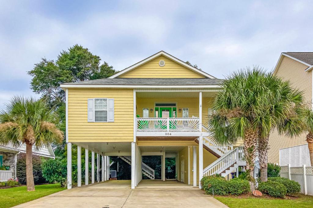 a yellow house with palm trees in front of it at A Shore Pleasure in Myrtle Beach