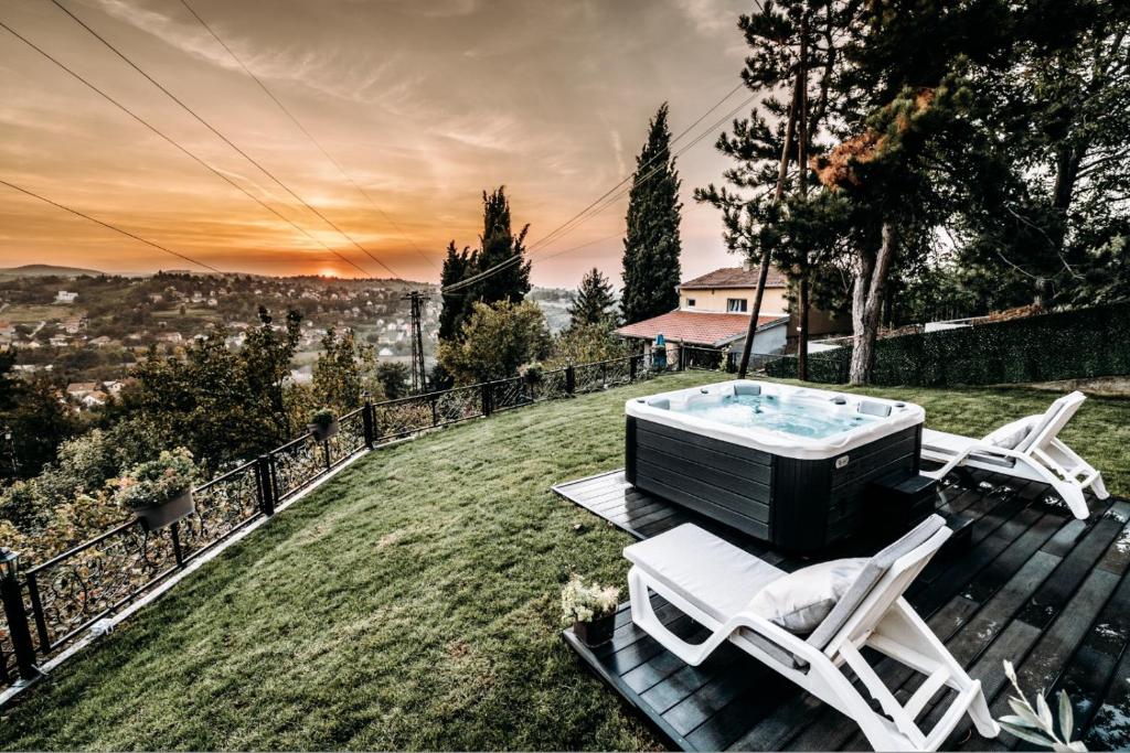 bañera de hidromasaje en una terraza con 2 sillas en The Cypress Villa & Vineyard II, en Sremska Kamenica
