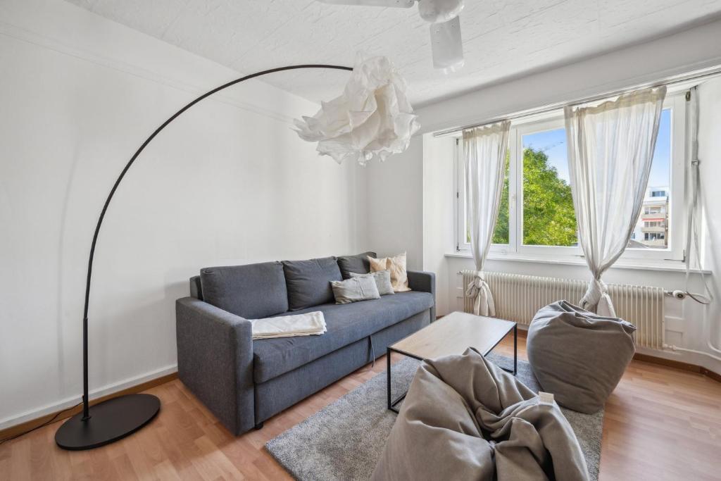 een woonkamer met een blauwe bank en een vloerlamp bij Homey Comfort in Oerlikon in Zürich