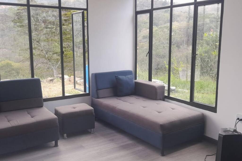 Habitación con sofá, silla y ventanas. en Cabaña en Guayabal de Siquima en Guayabal de Síquima