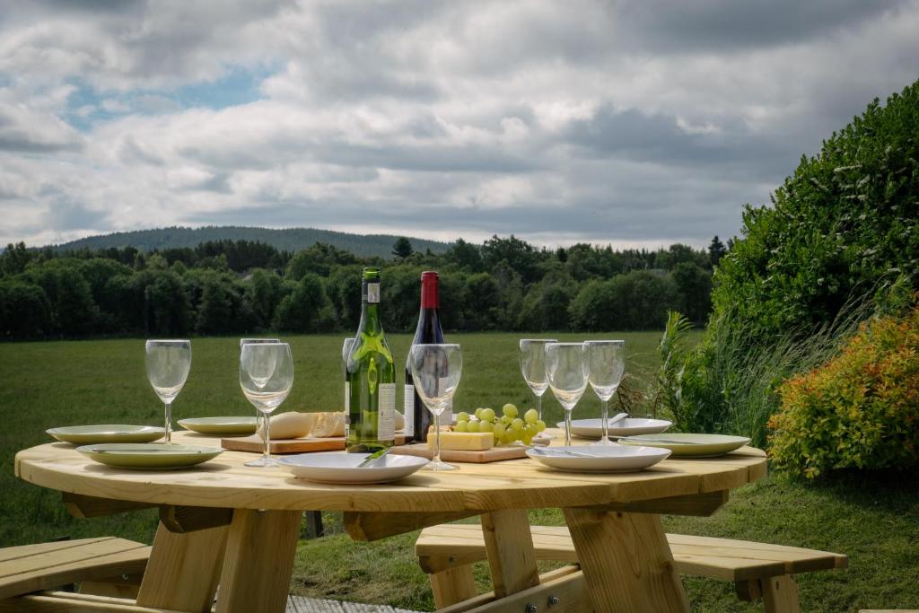 un tavolo in legno con bottiglie di vino e bicchieri di Burnbrae Lodge - Seasgair Lodges a Carrbridge