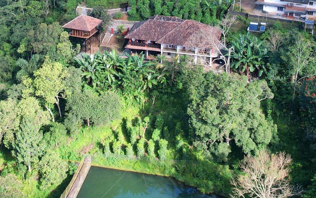 an aerial view of a house with a river and trees at Spice Forest Plantation Homestay, Thekkady in Vandiperiyār