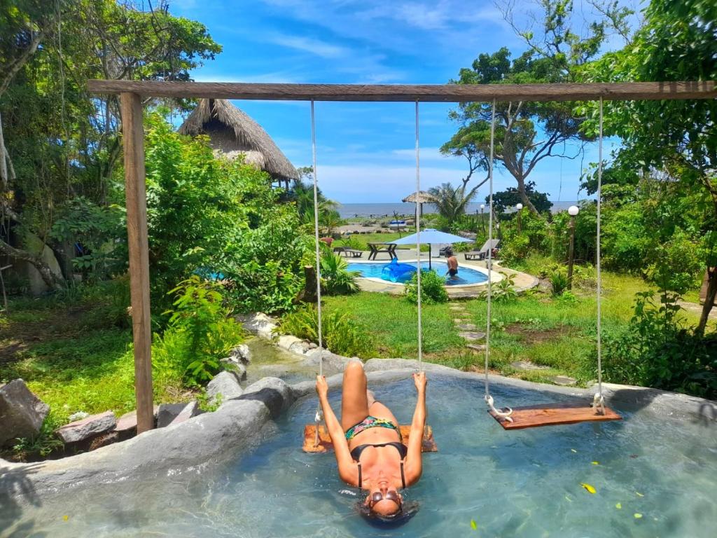 uma mulher deitada num baloiço na água num resort em Miravalle Eco Surf em Sonsonate