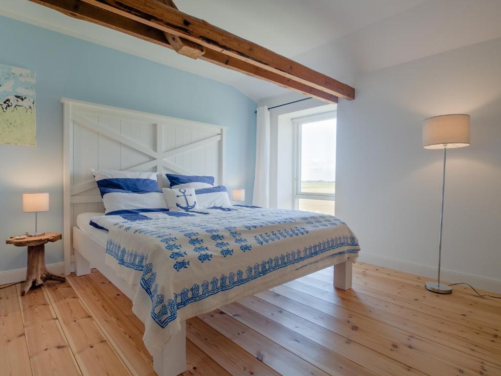 Un dormitorio con una cama con sábanas azules y blancas y una ventana en WattGut Pellworm, en Pellworm