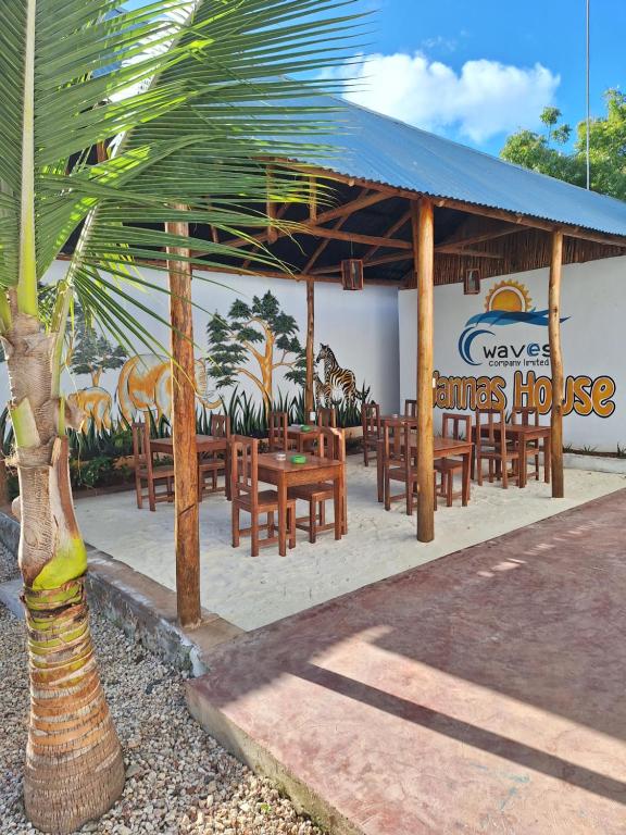 a restaurant with wooden tables and chairs and a palm tree at wannas house in Nungwi