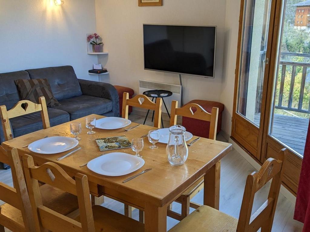 a living room with a wooden table with chairs and a television at Appartement Orcières Merlette, 3 pièces, 8 personnes - FR-1-262-170 in Orcières