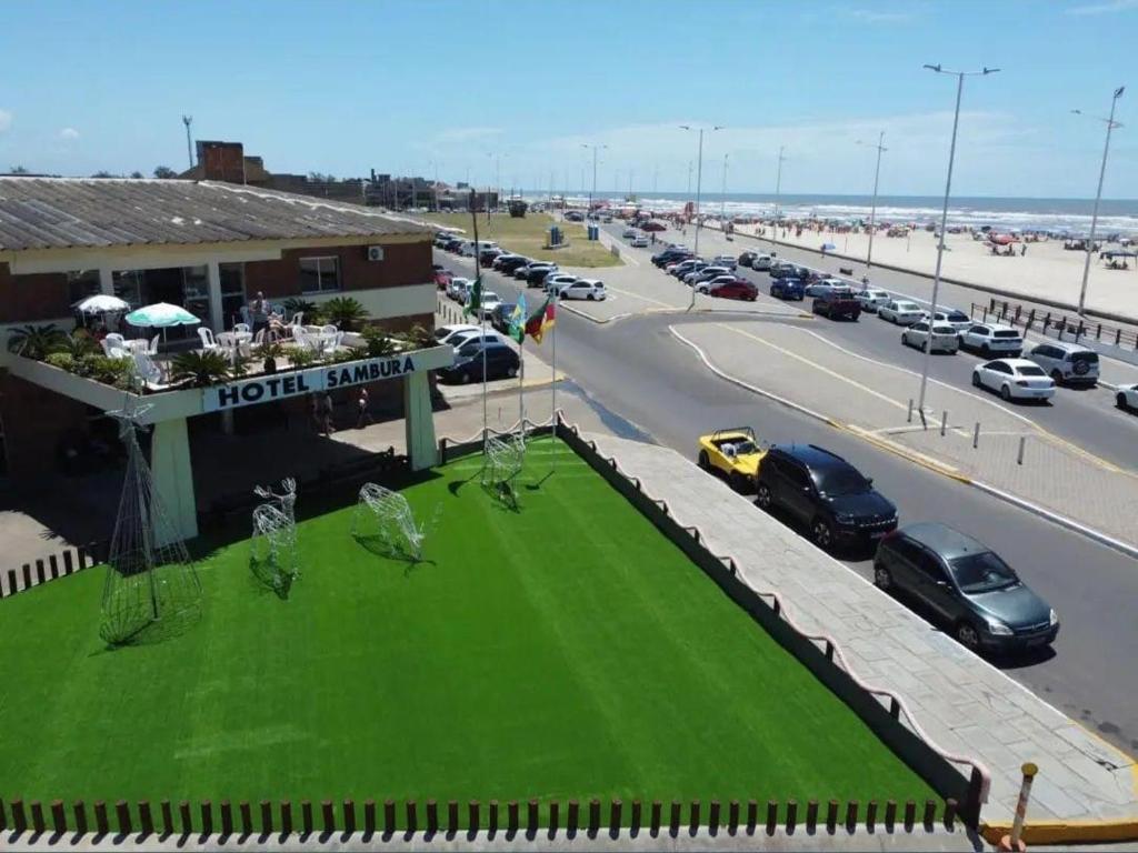 a hotel with a green lawn in front of a highway at Hotel Sambura in Imbé