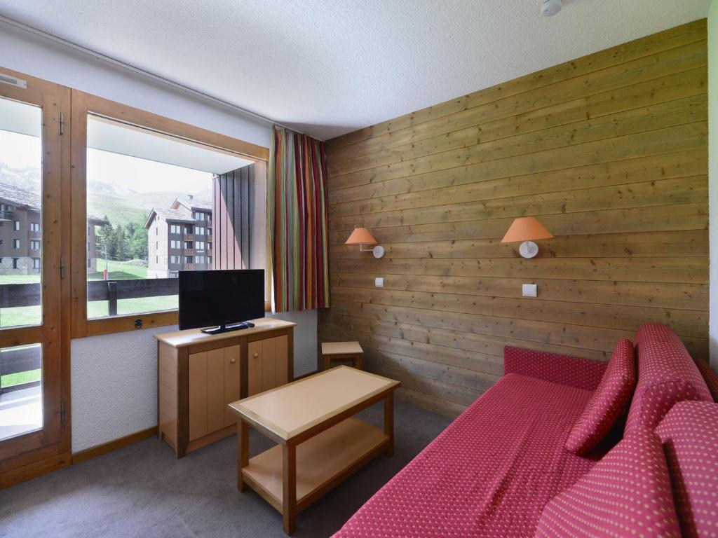 - une chambre avec un lit rouge et une télévision dans l'établissement Studio divisible au pied des pistes avec balcon et casier à skis - FR-1-181-2083, à La Plagne Tarentaise