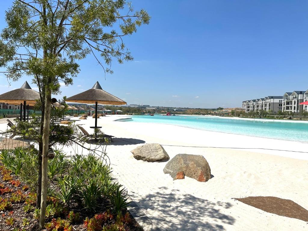 a beach with rocks and umbrellas and the water at Cosy Munyaka Waterfall Apartment in Midrand