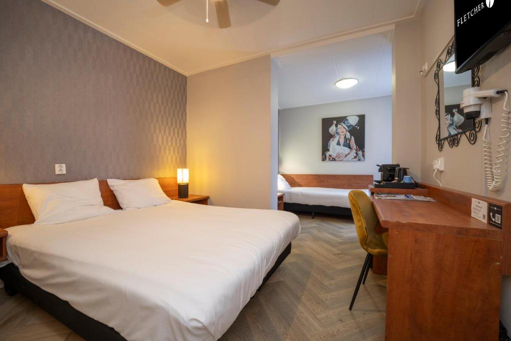 ein Hotelzimmer mit einem großen Bett und einem Schreibtisch in der Unterkunft Fletcher Hotel-Restaurant de Korenbeurs in Made
