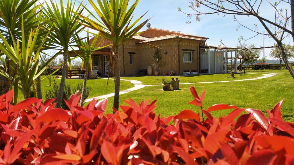 uma casa com flores vermelhas em frente a um quintal em Agriturismo La Dependance em Sorano
