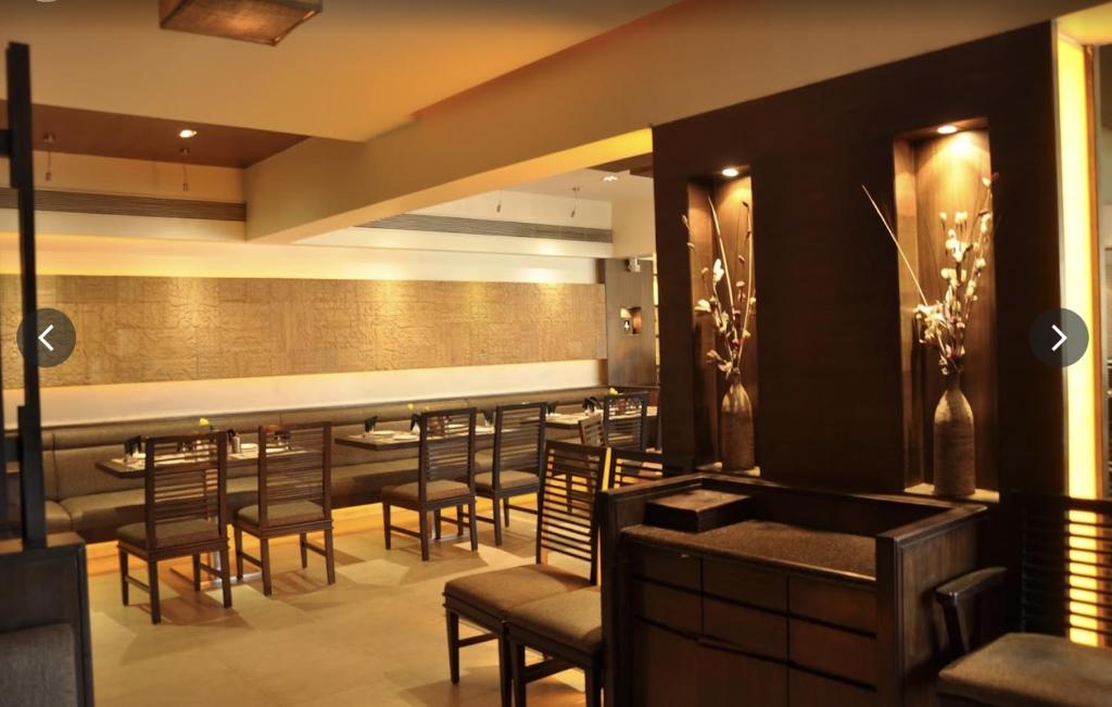a bar in a restaurant with chairs and tables at Rajhans Belliza Aashiana in Surat