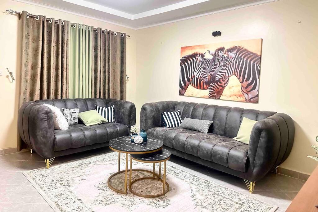 Luxurious 2 bedroom penthouse-Fully Furnished في كيتالي: غرفة معيشة مع أريكة جلدية وحمارتين وحشيتين