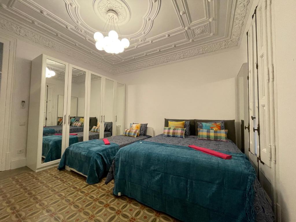 1 dormitorio con 2 camas y lámpara de araña en Bcn Centric Rooms en Barcelona