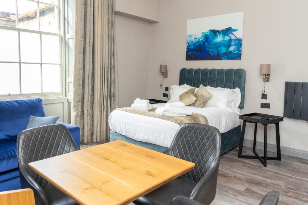 エディンバラにあるMONO Suites NEW TOWNのベッド、テーブル、椅子が備わるホテルルームです。