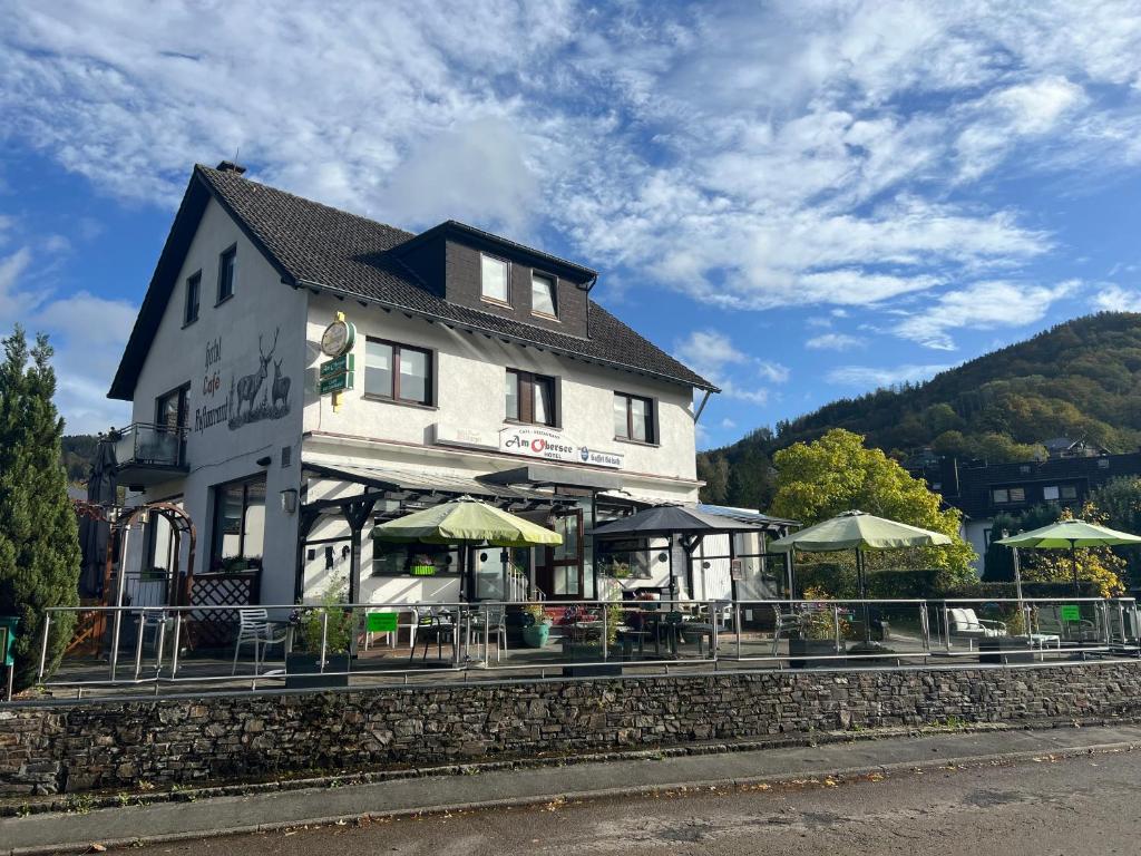 a large white building with tables and umbrellas at Am Obersee Hotel in Simmerath