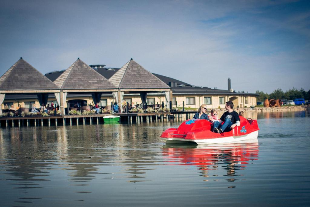 two people riding on a red boat in the water at Dubingių žirgynas in Dubingiai