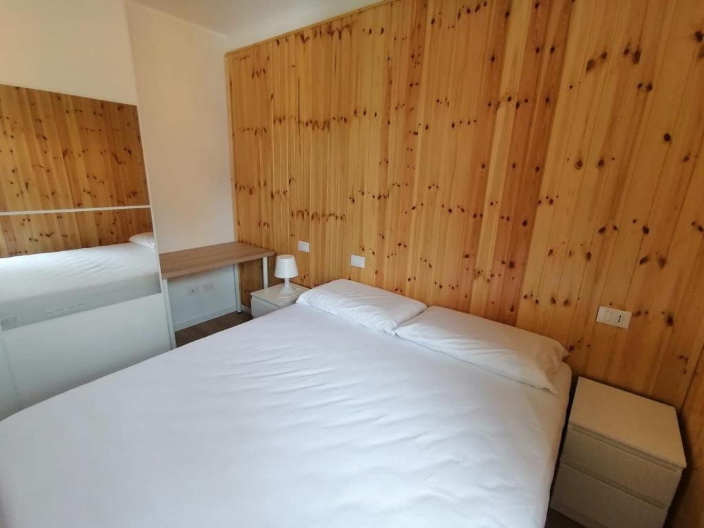 Habitación pequeña con cama blanca y paredes de madera. en Casa vacanza Lara, en Santa Brigida