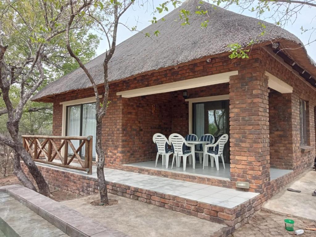 a brick house with chairs and a table on a porch at Le Lion Dort in Marloth Park