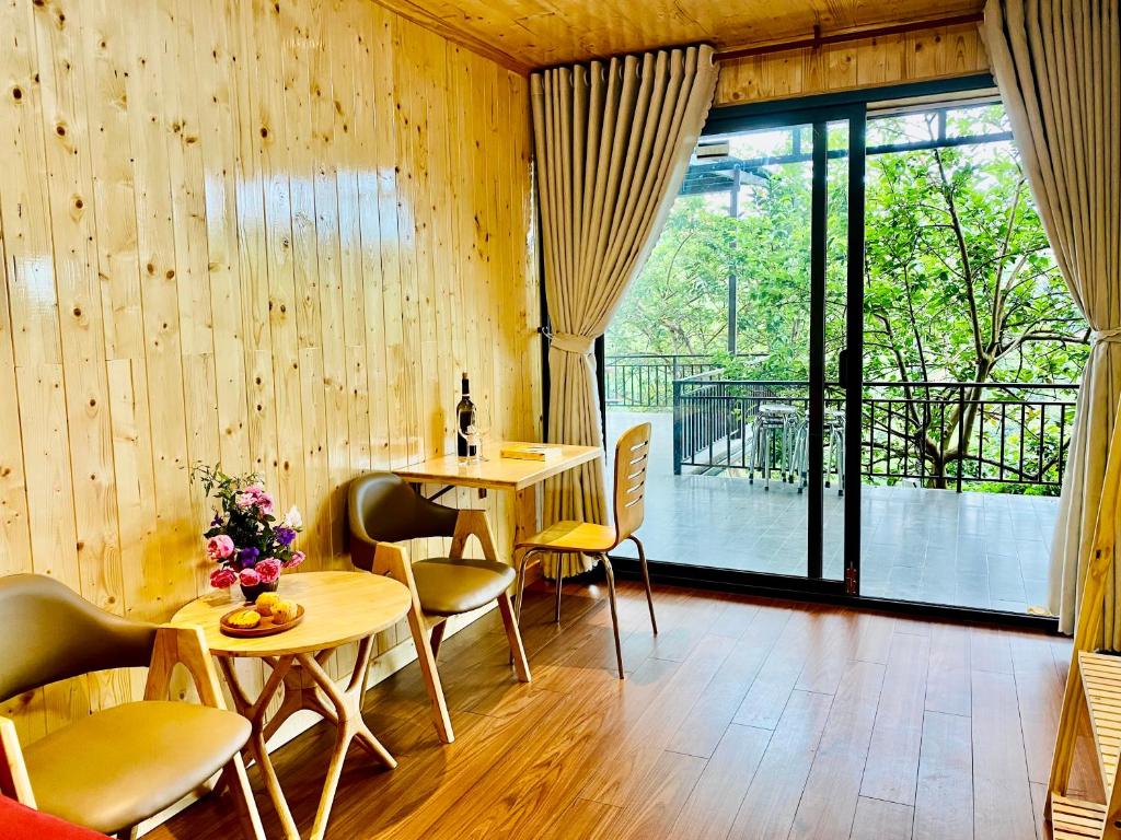 Habitación con paredes de madera, mesa y sillas. en Mimoza Homestay Cầu Đất, en Xuân Trường