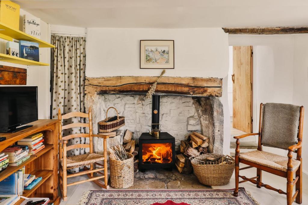 a living room with a fireplace and a chair at Mount Pleasant Cottage Painswick in Stroud