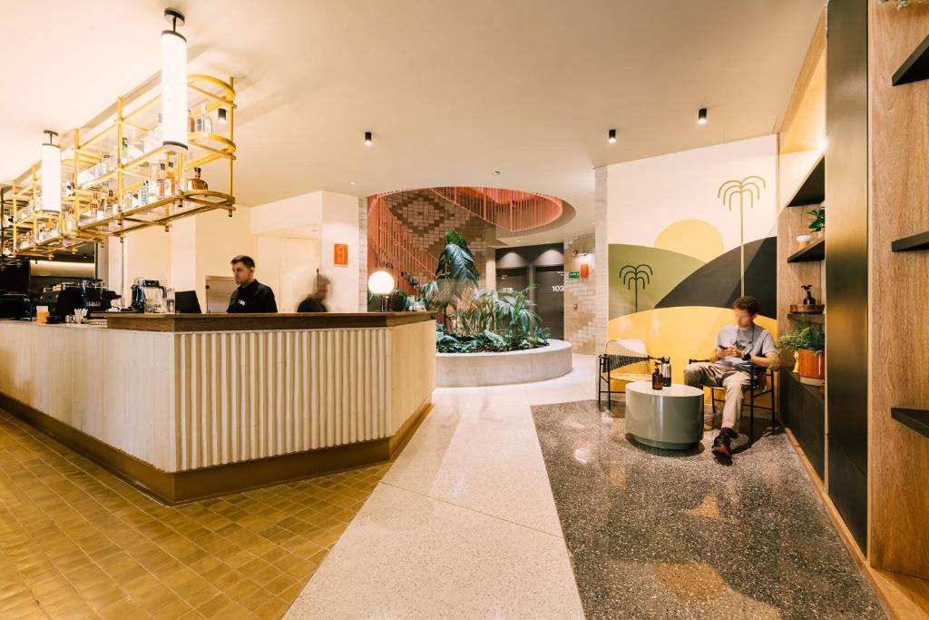 a lobby of a restaurant with people sitting at a counter at The Somos Bold Hotel in Medellín