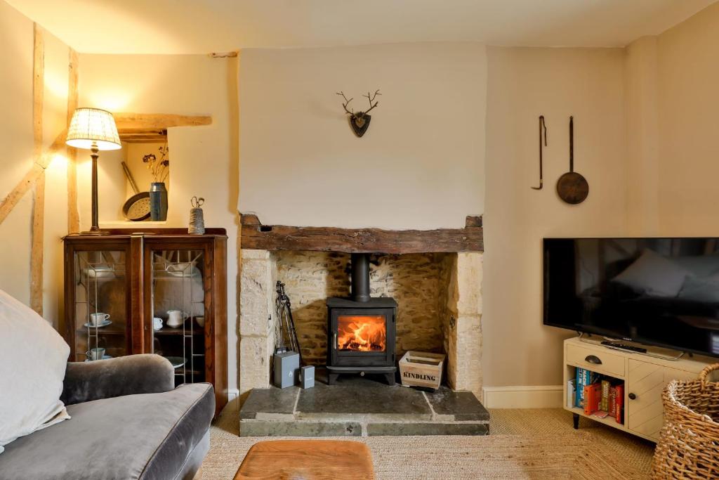 a living room with a fireplace and a tv at Jasmine Cottage, Upper Slaughter, Cotswolds in Cheltenham