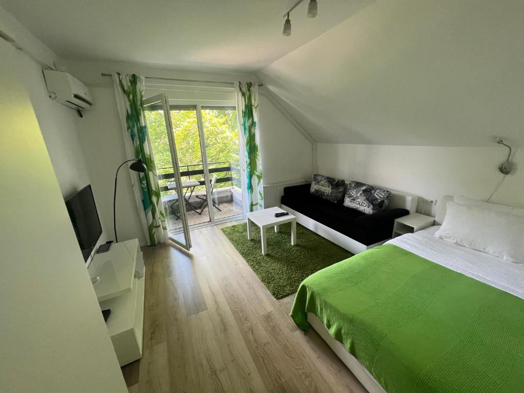 een slaapkamer met een groen bed en een bank bij Plitvice Studio Sara in Plitvička Jezera