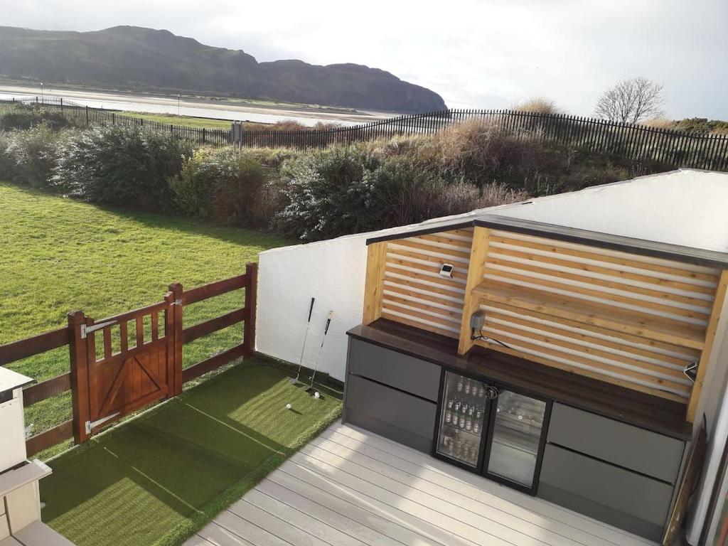 a house with a deck with a view of the beach at Seaside Escape - Deganwy Beach Cottage - Sea Views & Golf Course Views in Deganwy