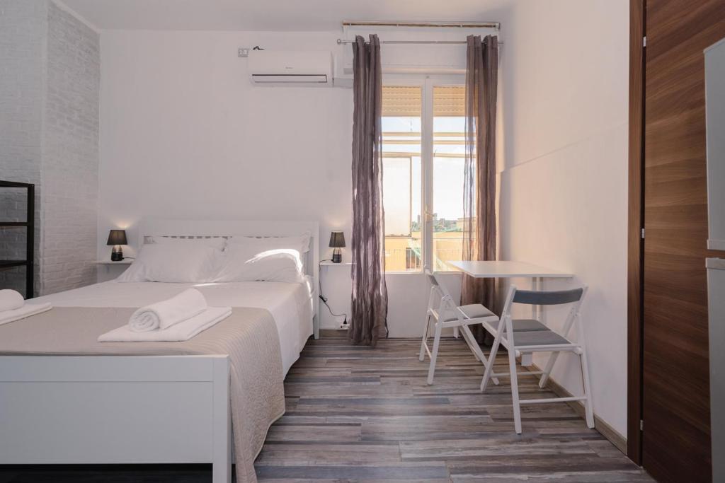 1 dormitorio blanco con 1 cama, mesa y sillas en Galleria Del Reno, en Bolonia