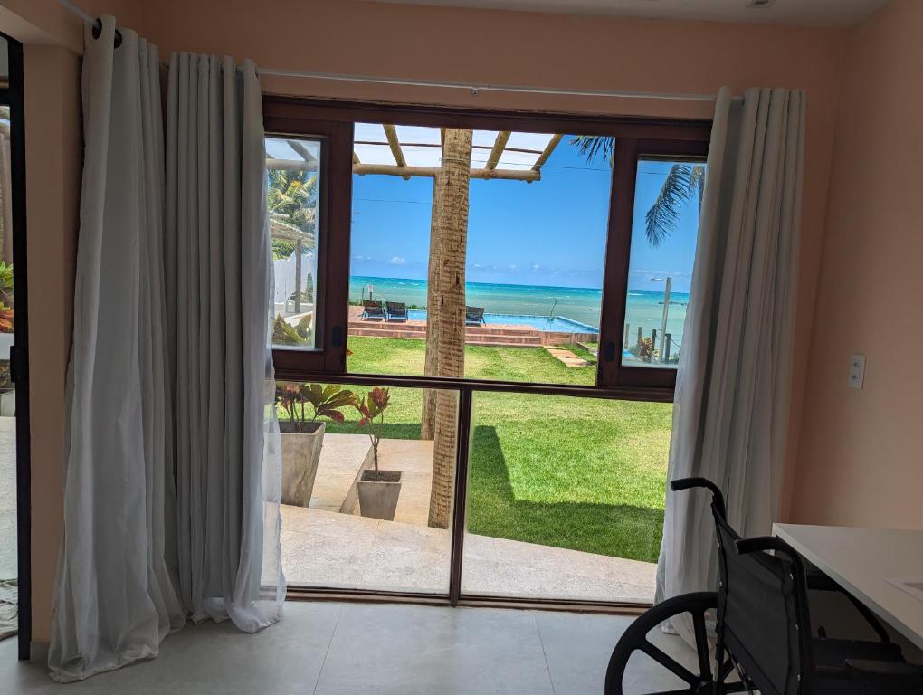 a room with a large window with a view of the ocean at Slater's House - Casa de praia em frente ao mar in Paripueira