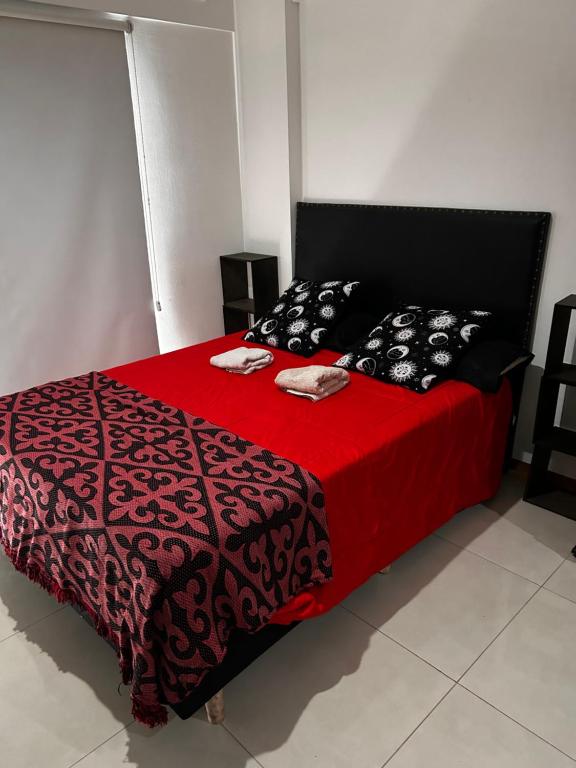 een bed met een rood en zwart dekbed en kussens bij Loft privado Berazategui in Berazategui
