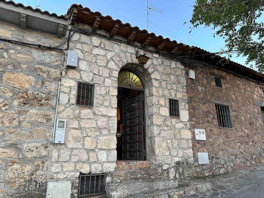 um antigo edifício de pedra com uma grande porta de madeira em Bodega típica en El Molar sin camas ni dormitorios em El Molar