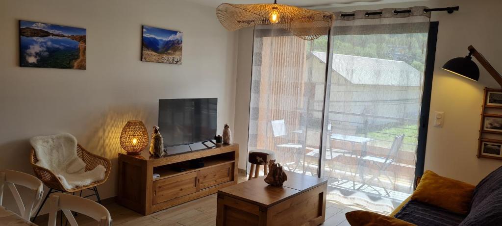 uma sala de estar com uma grande janela e uma televisão em Appt à Ancelle pied des pistes em Ancelle