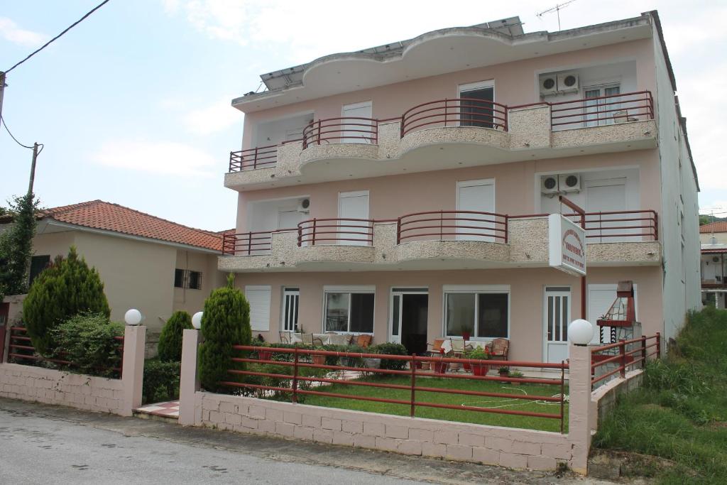 a white building with a red fence in front of it at Kondylenia Rooms in Loutrá Vólvis