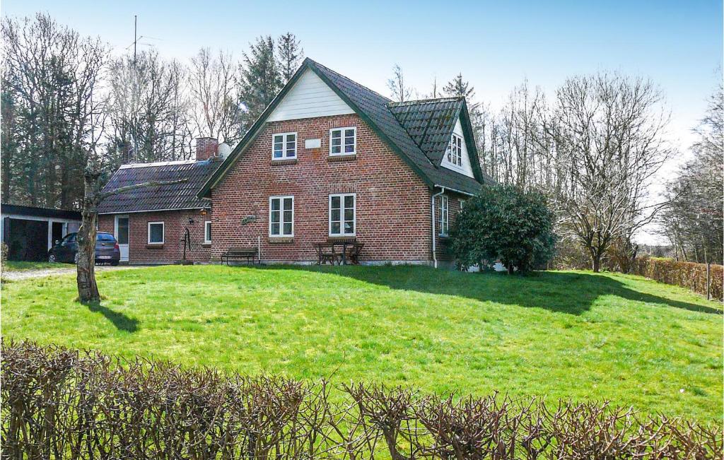 a large red brick house on a green lawn at 3 Bedroom Beautiful Home In Tistrup in Tistrup