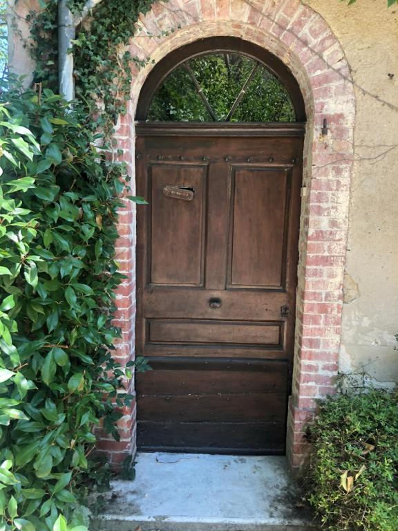 een boog met een houten deur in een bakstenen muur bij Maison de 1820 dans un écrin de verdure de 2 ha in Entrechaux