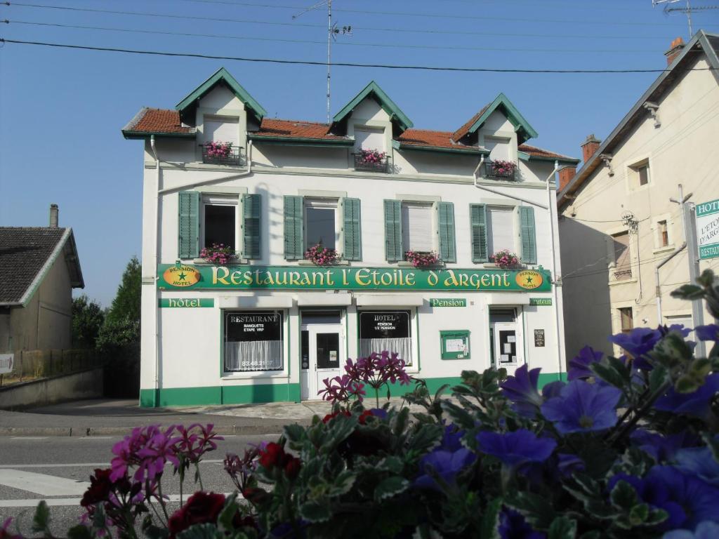 a white and green building with flowers in front of it at L Etoile d'Argent in Varangéville