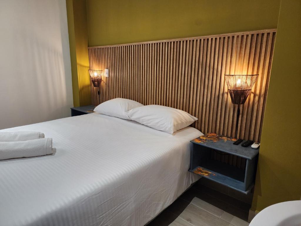 een slaapkamer met een groot wit bed en 2 lampen bij Casa Arte Coliving in Pereira