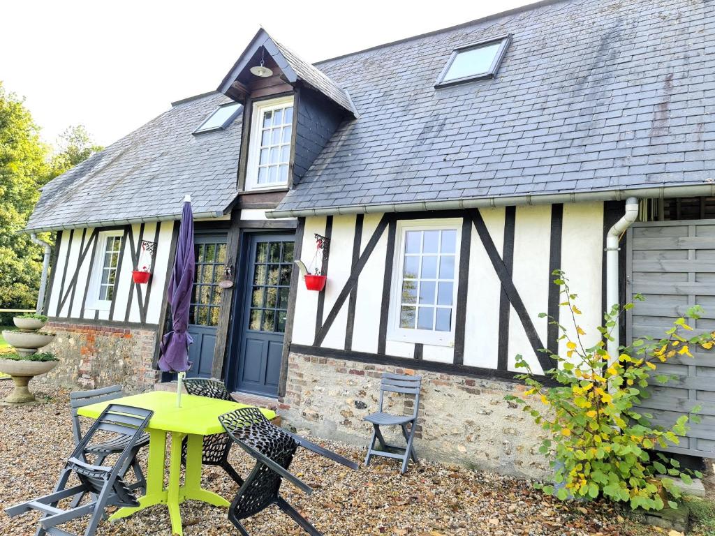 una casa con un tavolo e sedie di fronte di Maison normande a Freneuse-sur-Risle