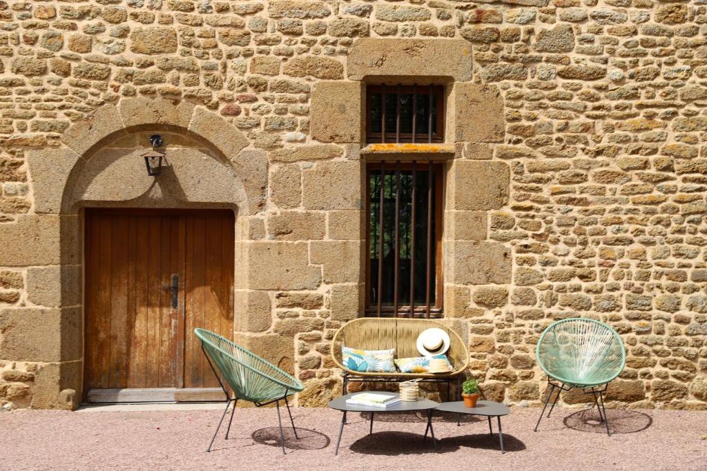 zwei Stühle und ein Tisch vor einem Gebäude in der Unterkunft Manoir avec Piscine et Jacuzzi en Suisse Normande in La Carneille