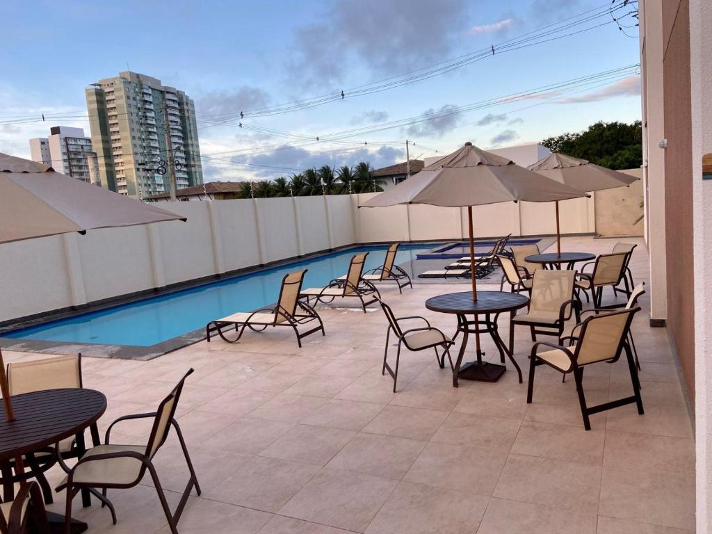 eine Terrasse mit Tischen und Stühlen neben einem Pool in der Unterkunft Apê do Tigas - Praia dos Milionários in Ilhéus