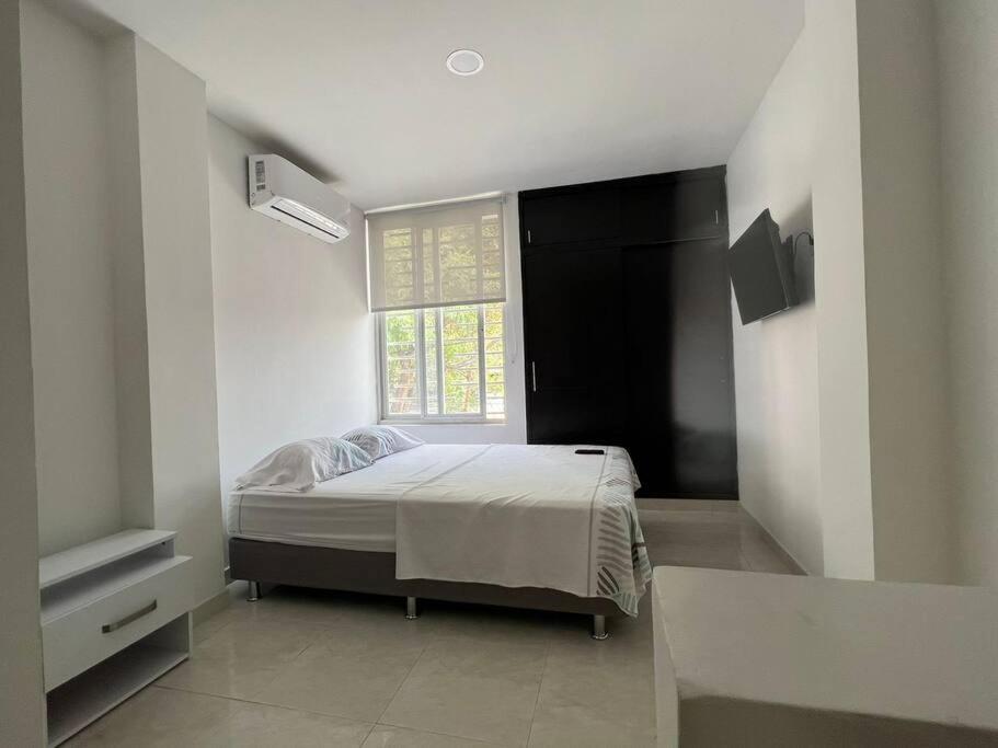 ein weißes Schlafzimmer mit einem Bett und einem Fenster in der Unterkunft apartaestudió dúplex Neiva in Neiva