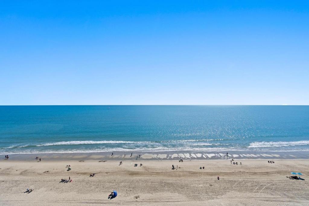 um grupo de pessoas numa praia perto do oceano em Holiday 1111 - Charming oceanfront condo with beachfront panoramic views, Pools em Myrtle Beach