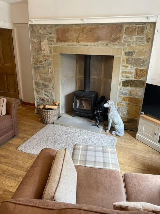 a living room with a couch and a fireplace at Hawksworth Cottage - Grassington Village Location in Grassington