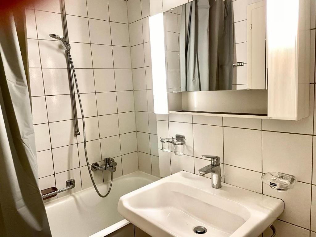 a bathroom with a sink and a shower with a mirror at appartement Montreux centre lac in Montreux