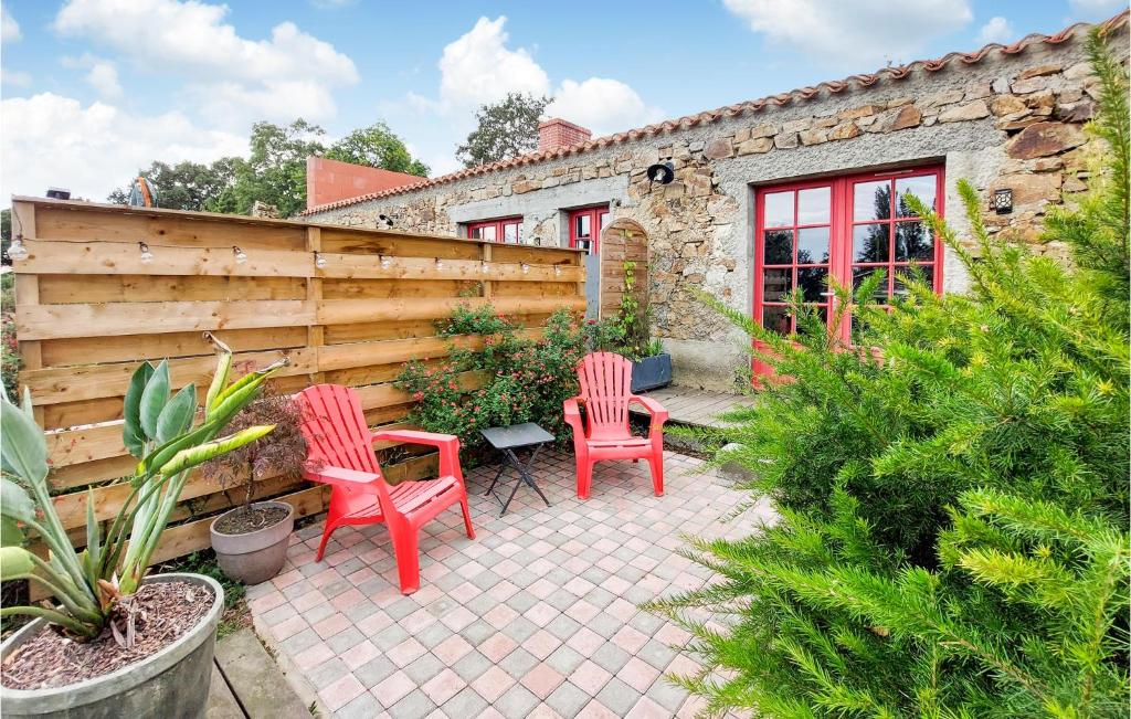 un patio con 2 sillas rojas y una valla de madera en Nice Home In Frossay With Kitchen, en Frossay