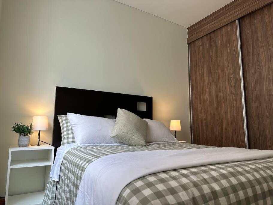 a bedroom with a large bed with two lamps at Dpto agradable cerca del Aeropuerto y Foro Sol in Mexico City